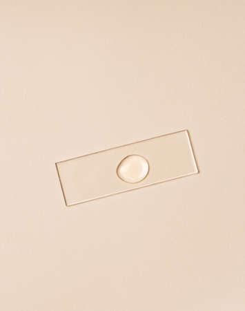 A drop of a transparent liquid cosmetic product on a glass surface. Beauty and medicine concept. Top view, copy spaceの写真素材