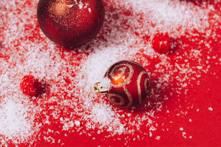 Red baubles of Christmas decoration with snow on a red background. Christmas balls and fluffy circles. Minimalistic style. Flat lay.の写真素材