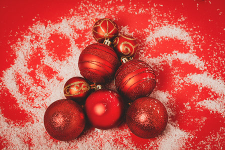Christmas tree made from red balls with snow on a red background. Flat lay, top view, copy space.の写真素材