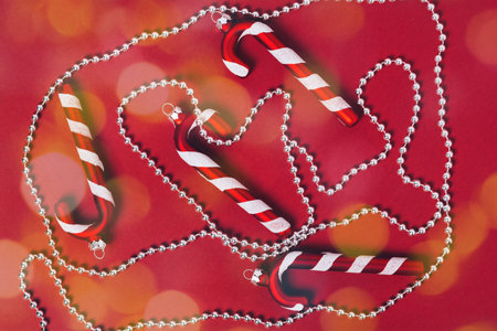 Christmas decoration on a red background. christmas lollipops and new year's beads for the tree. Flat lay.の写真素材