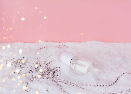 Facial cosmetic product in the snow with christmas decoration. Liquid skin or hair care product. Christmas and holiday concept. Front view and copy spaceの写真素材