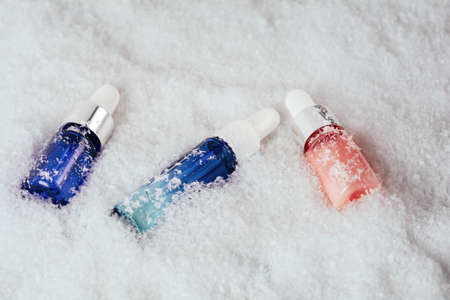 Serum glass bottle set in the snow. Liquid skin or hair care product. Christmas and holiday concept. Top view and copy spaceの写真素材