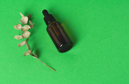 Glass bottle with liquid on a green background.の写真素材