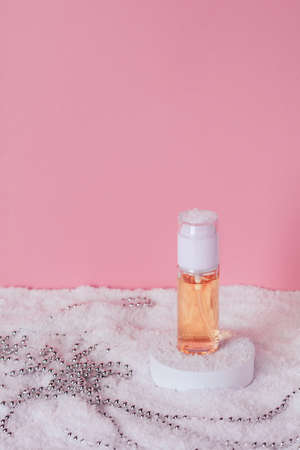 Facial cosmetic product on the podium in the snow. Liquid skin or hair care product. Front view and copy space, verticalの写真素材
