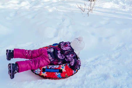 Funny child in violet clothes ride on tubing