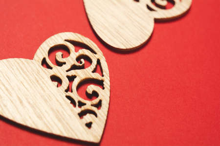 Wooden hearts on a red background. Background for the holiday of Valentine's Day. The concept of love, romance and tendernessの写真素材