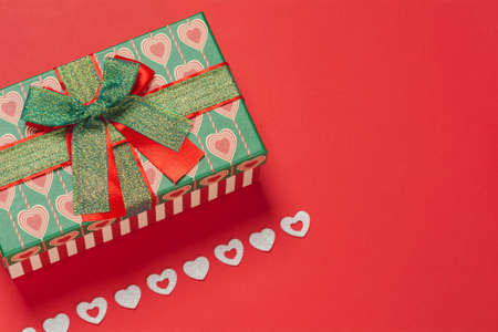Gift box and shiny white hearts on a red background. Background for the holiday of Valentine's Day. The concept of love, romance and tendernessの写真素材