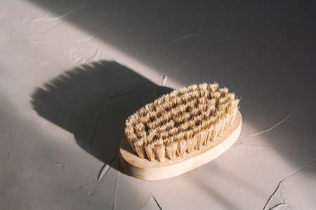 Natural brush for dry massage on gray texture background. Beauty, spa and wellness concept. Front view, copy spaceの写真素材