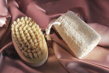 Natural washcloth and brush for dry massage on a shiny pink fabric background. Beauty, spa and...