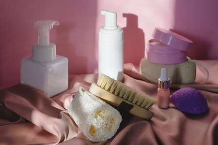Spa cosmetic products and eco friendly bathroom accessories on a shiny pink fabric background. Beauty, spa and wellness concept. Focus on accessoriesの写真素材