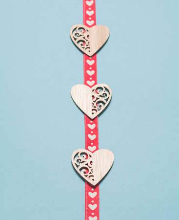 Wooden hearts with a red ribbon in white hearts on a blue background. Background for the holiday of Valentine's Day. The concept of love, romance and tendernessの写真素材