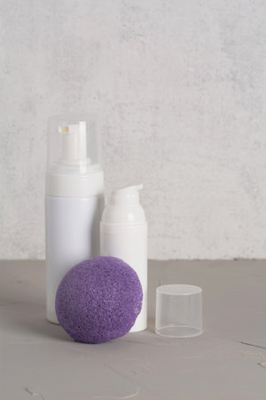 Beauty, spa and wellness concept. Facial cosmetic products, konjac sponge on gray texture background. front viewの写真素材