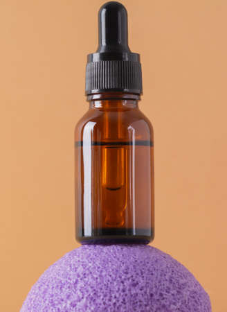 Beauty, spa and wellness concept. Close-up cosmetic bottle with serum or essence, konjac sponge on beige background. front viewの写真素材