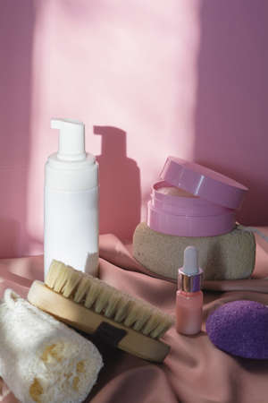 Spa cosmetic products and eco friendly bathroom accessories on a shiny pink fabric background. Beauty, spa and wellness concept. Verticalの写真素材