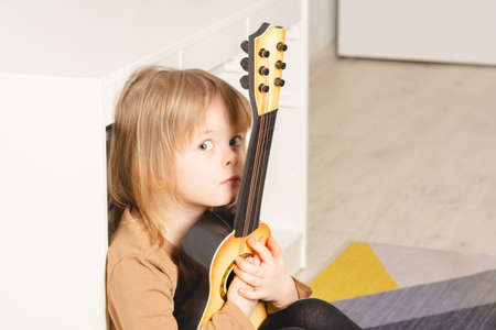 Child at home learning to play the guitar. Leisure and education at homeの写真素材
