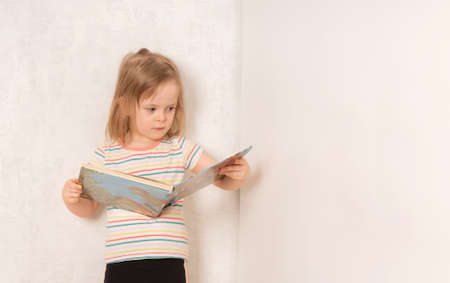 Serious child standing and studying a bookの写真素材