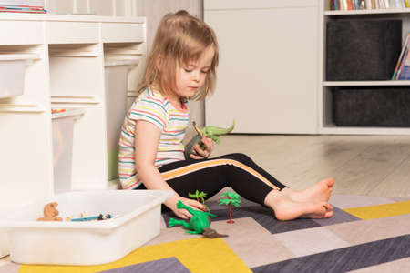 Child playing on the floor in dinosaurs in the roomの写真素材