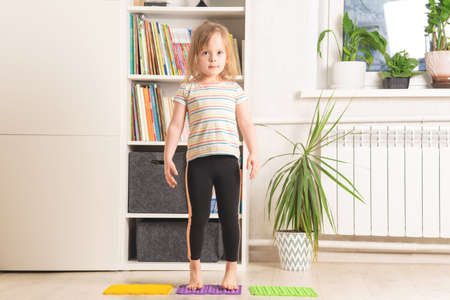 The child trains at home: fitness, yoga, exercises. Distant training with personal trainer, social distance, online education concept. Physical and mental health trendsの写真素材
