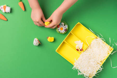 Children's hands lay out a set of decorative ornaments: rabbits, chickens, carrots, a nest with eggs. Preparing for a happy easterの写真素材