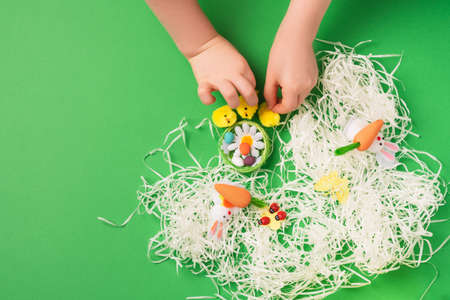 Children's hands arrange decorative decorations for Easter holiday: rabbits, chickens, carrots, a nest with eggs. Preparing for a happy easter. copy spaceの写真素材