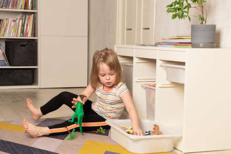 Child playing on the floor in dinosaurs in the room. development in the game. Leisure and education at homeの写真素材