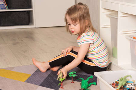 Child playing on the floor in dinosaurs in the room. development in the game. Leisure and education at homeの写真素材