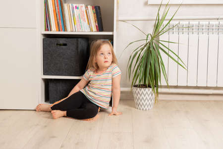 Child sits on the floor in the room near the bookcase. Leisure and education at home. Children's creativity and educationの写真素材