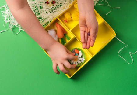 Children's hands lay Easter decorative eggs in a decorative nest. Preparing for a Happy Easterの写真素材