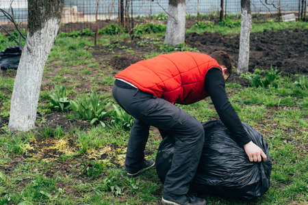 A man removes a large bag of garbage