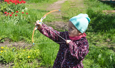 Child 4-year-old shoots up with a bow outside. side view.の写真素材