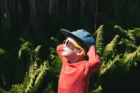 Girl in sunglasses and a cap stands outdoorsの写真素材
