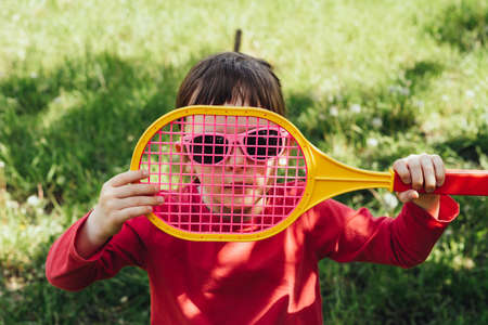 Child girl looking at camera through badminton racketの写真素材