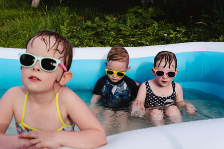 Wet serious children in the pool in sunglasses. Focus on children in the background. Summer is a time of pleasure and funの写真素材