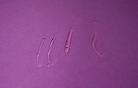 Cosmetic samples texture with bubbles. Smears of transparent liquid cosmetics on a purple backgroundの写真素材