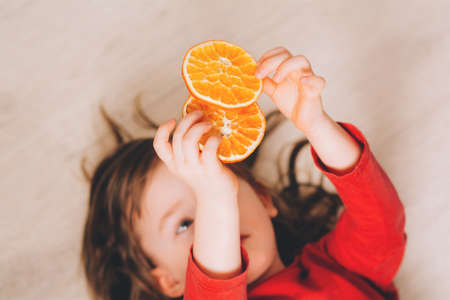 Cute little girl holding dry orange slicesの写真素材