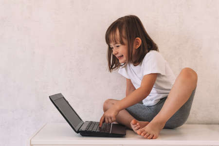 Smiling girl sitting on the closet and using a laptopの写真素材