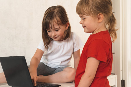 Two girls use laptop at home for learning and communicationの写真素材