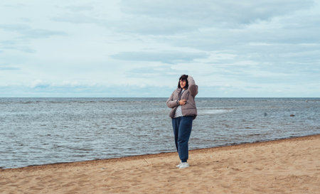 Woman on the beach by the sea in cold weatherの写真素材