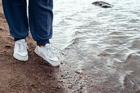 Legs close-up on the sandy shore of a cold bay