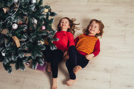 Happy funny children lying on the floor next to the Christmas treeの写真素材