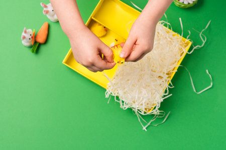 Children's hands arrange decorative decorations for easter: rabbits, chickens, carrots, a nest with eggs. Preparing for a happy easterの写真素材