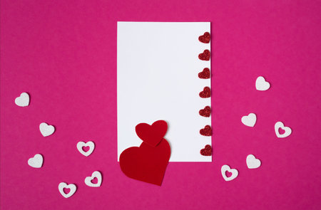 Red hearts on a white sheet. Mockup for a postcard