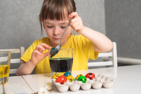 Child color quail eggs with food coloring. Girl painting Easter eggs.の写真素材
