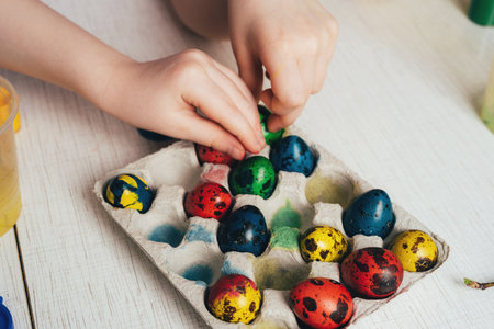 Children's hands take colored quail easter eggs. Preparing for a happy easter holidayの写真素材