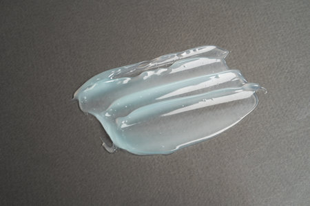 Close-up smear of transparent cosmetic product with bubbles on gray background. texture and...
