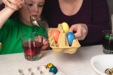 Grandmother helps her grandson paint Easter eggs. easter preparationの写真素材