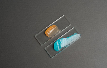 Samples of a multicolored cosmetic product on a laboratory glass on gray background. selfcare trends