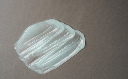 Close-up smear of transparent cosmetic product with bubbles on gray background. texture and...