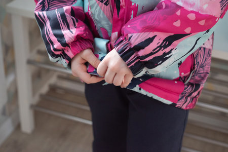 Close-up of the hand of a child who zips up his jacket. Development of an independent childの写真素材