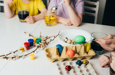 Childrens hands color eggs with food coloring.
